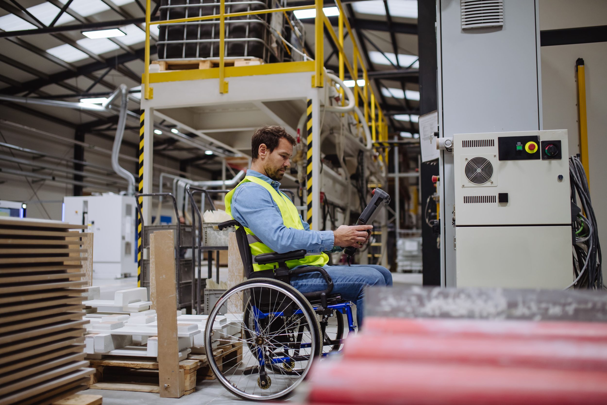 A man sat in a wheelchair at work whilst operating a device for manufacturing